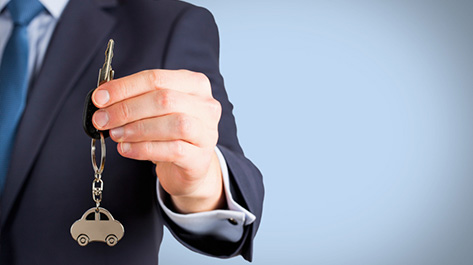 Man handing over the keys to a car that you used a credit union for a car loan