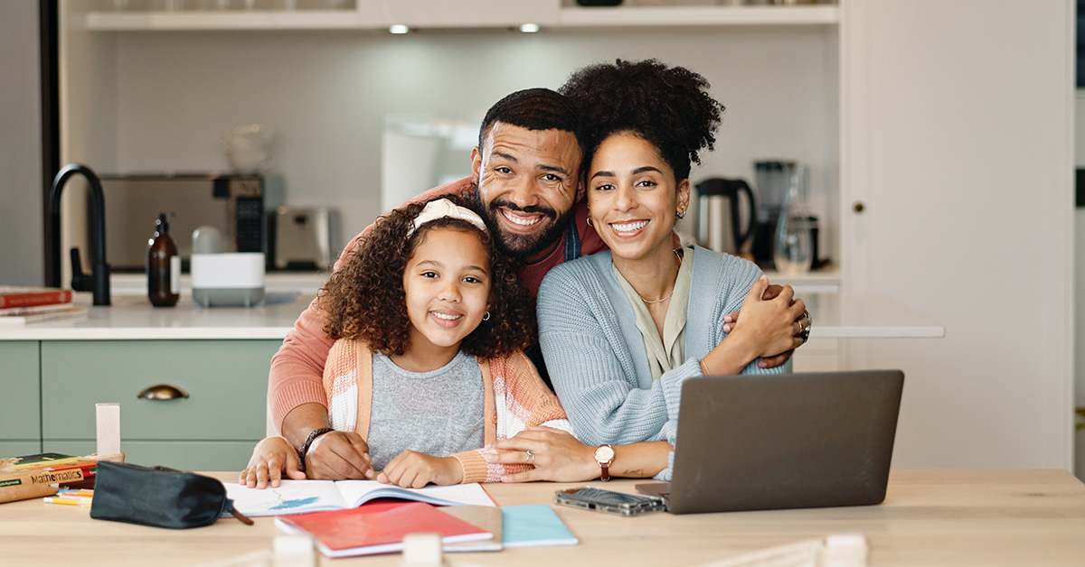 Parents and child reviewing school information on a laptop surrounded by notebooks and school supplies, showing online safety during back to school season.