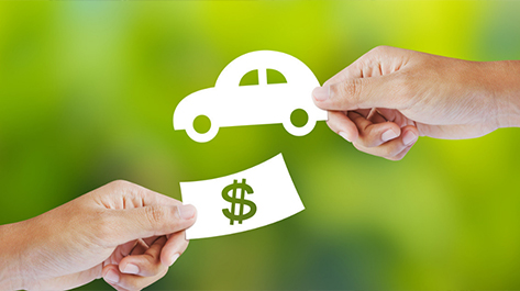 A paper car and money being shared when a person cosigns for a car loan