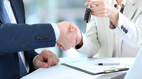 Two people exchanging car keys for their new car