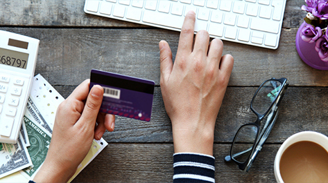 Hands with Velocity Community Credit Card and looking about information on it online